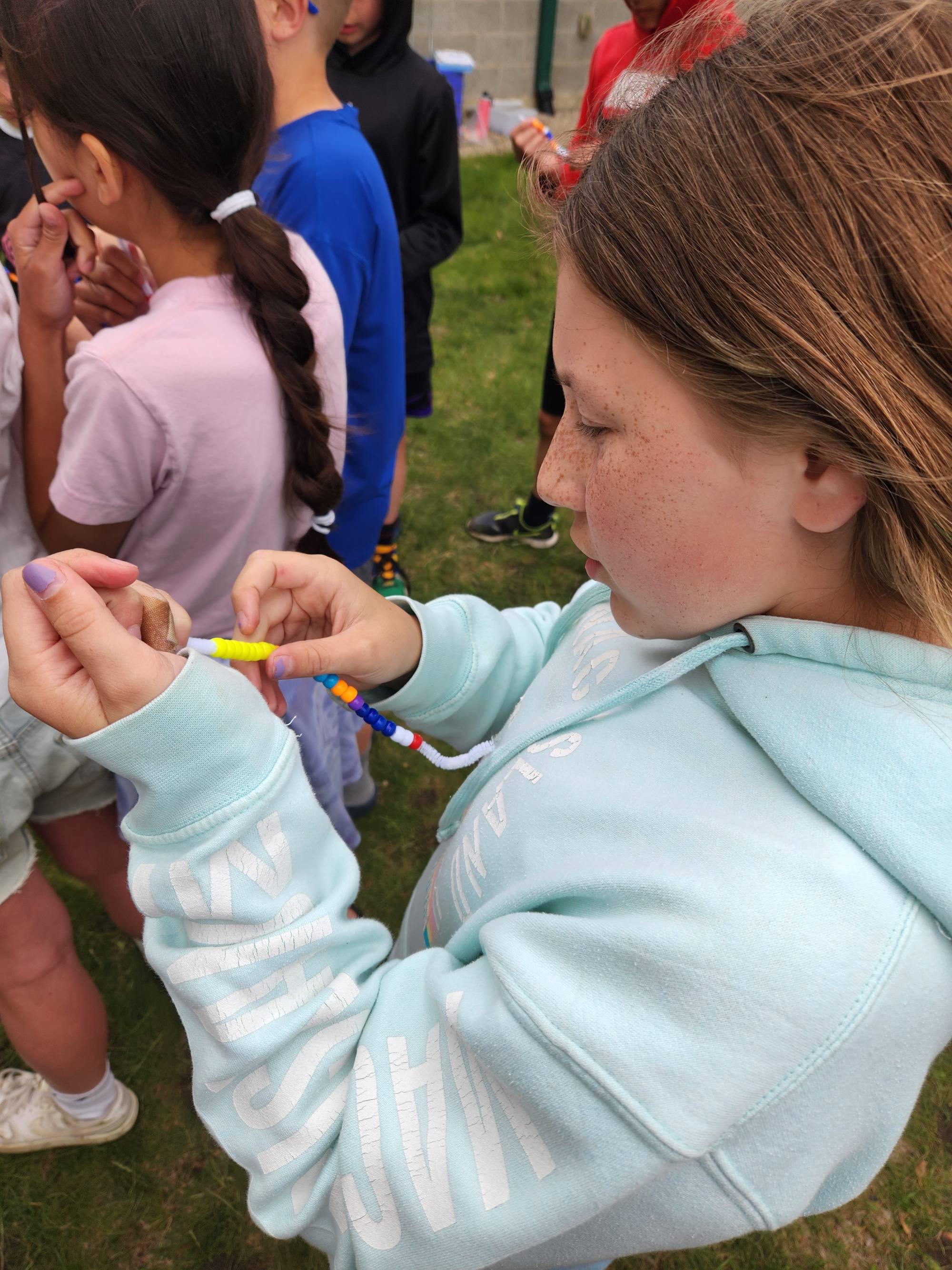 Student putting bead on bracelet